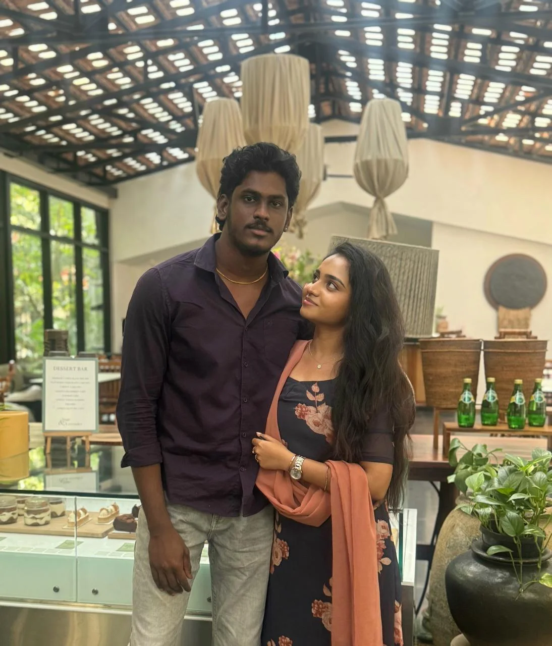 A couple standing close together inside a softly lit restaurant
