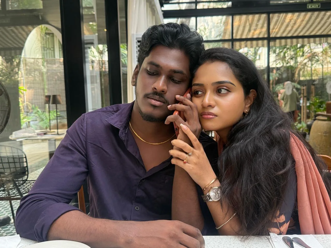 A couple sitting close together at a table and sharing a soft candid moment