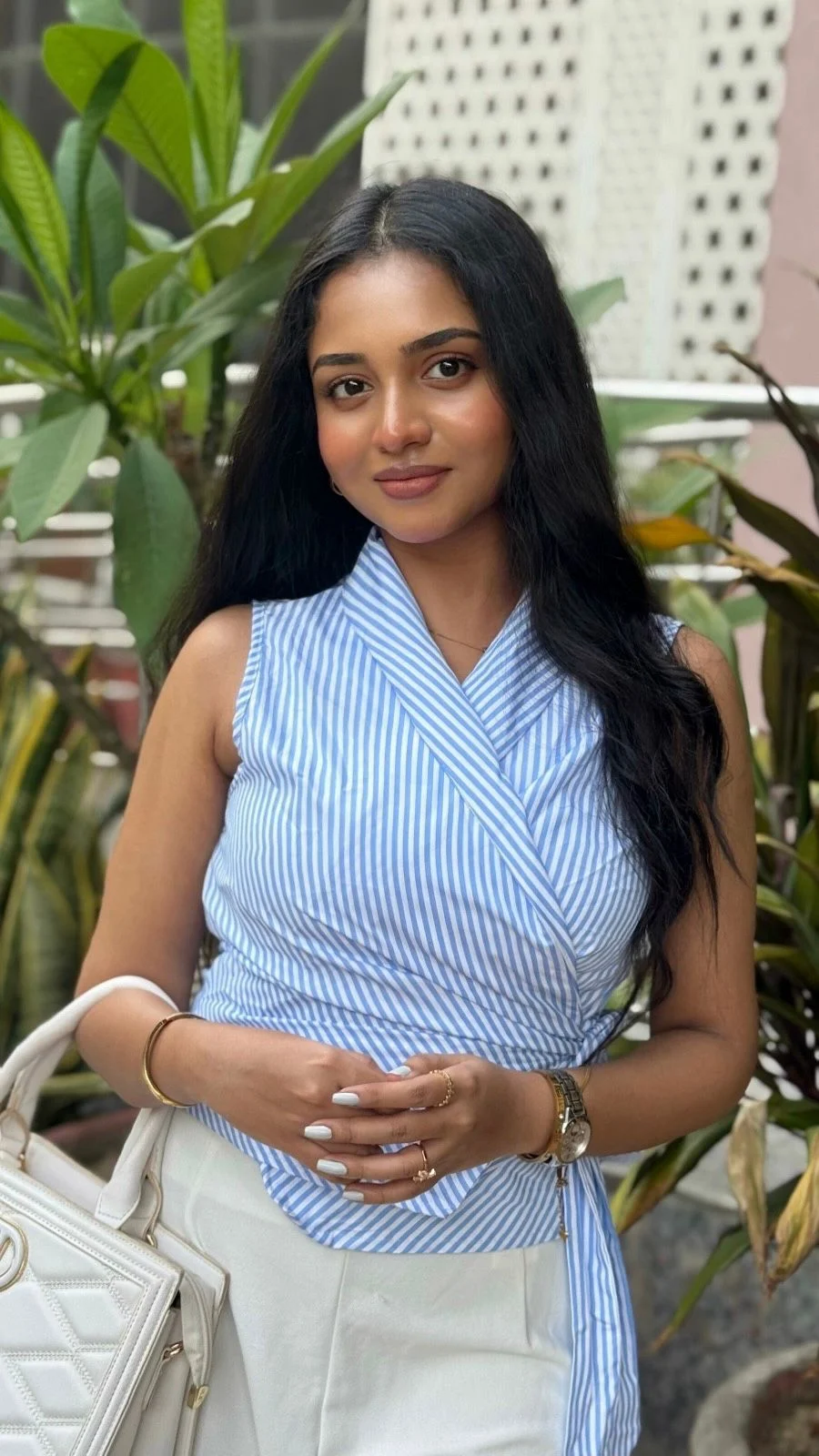 Niktha standing beautifully outdoors in a blue striped top